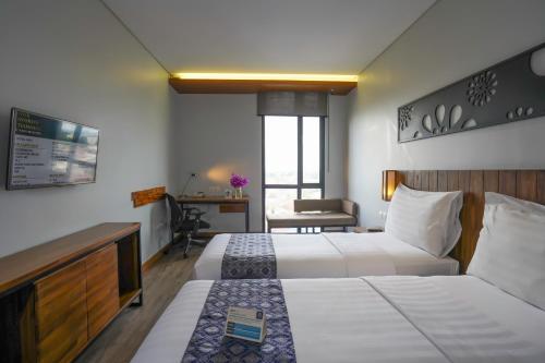 巨港巴提卡巨港酒店的酒店客房配有两张床和一张书桌