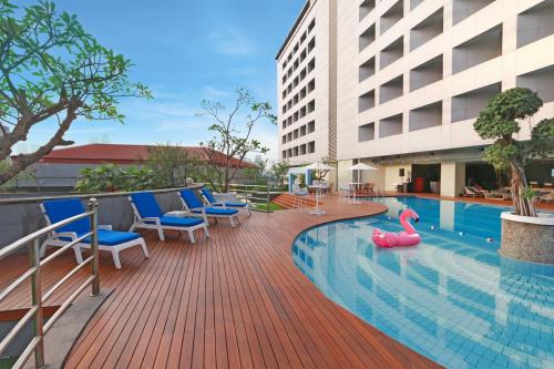雅加达Hotel Bidakara Jakarta的大楼内一个带椅子和泳池玩具的游泳池