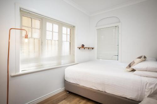 悉尼Suburban Two-bed Apartment with Parking and Patio的白色的卧室设有床和窗户