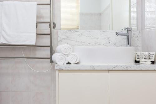 悉尼Suburban Two-bed Apartment with Parking and Patio的浴室配有盥洗盆、淋浴和毛巾