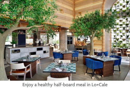 迪拜Crowne Plaza Dubai Marina, an IHG Hotel的一间空餐厅,配有桌椅和树木