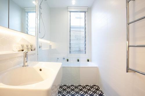 悉尼Spacious 3-Bed Family House with Courtyard的白色的浴室设有水槽和浴缸。