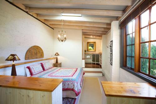 卢拉Little Haven Leura Cottage with Spa Bath and BBQ的卧室配有床、桌子和窗户。