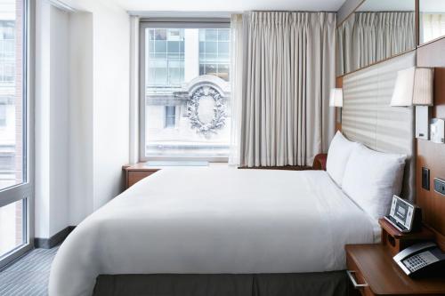 纽约Club Quarters Hotel Grand Central, New York的卧室设有一张白色大床和一扇窗户。