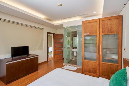 岘港Ocean Sunny Villas Da Nang的一间卧室配有一张床和一台平面电视