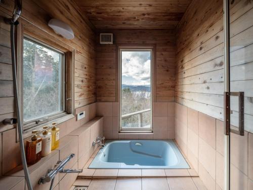 伊东Oceanic House TAMATEBAKO的一间带浴缸的浴室,位于一个窗口的房间