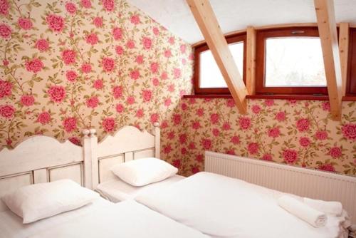 SieksātePiena muiža - Berghof Hotel & SPA的卧室内的两张床,墙上挂着鲜花