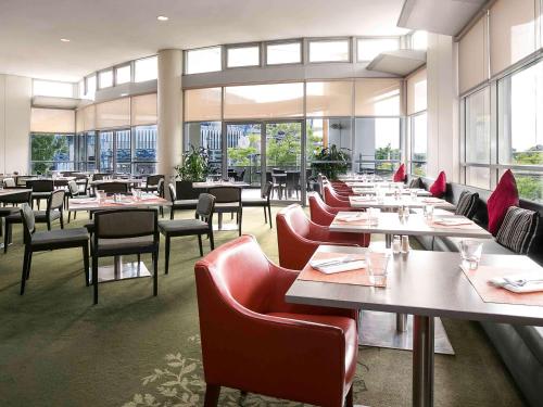 悉尼诺富特悉尼奥林匹克园大酒店的用餐室设有桌椅和窗户。