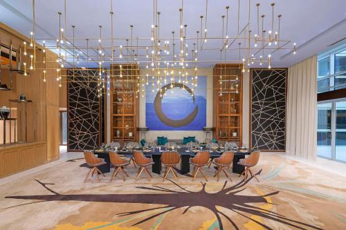 迪拜Andaz by Hyatt – Palm Jumeirah的一间带桌椅和吊灯的用餐室