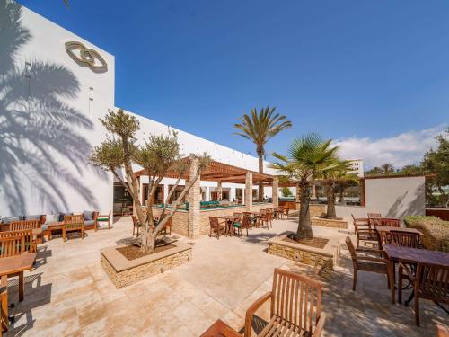 阿加迪尔Sofitel Agadir Royal Bay Resort的一个带桌椅的庭院,棕榈树