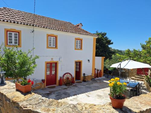 马夫拉Casa das Janelinhas - Cottage near Sintra, Mafra, Ericeira的白色的房子,设有红色的门和庭院