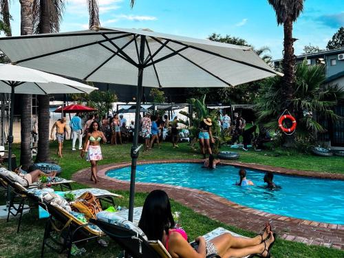 SandtonMonte La Vue Hotel的一群人坐在游泳池周围,带一把遮阳伞
