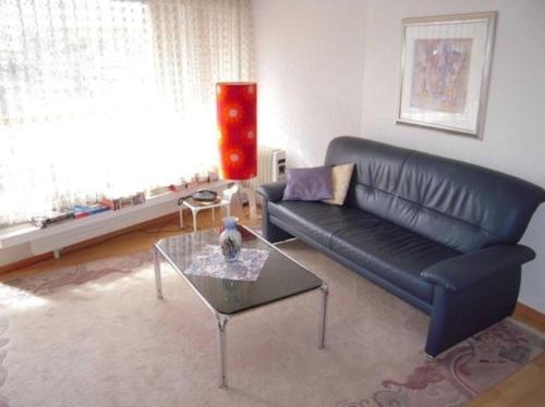 韦吉斯Appartement Alpenblick C3的客厅配有黑色真皮沙发和玻璃桌