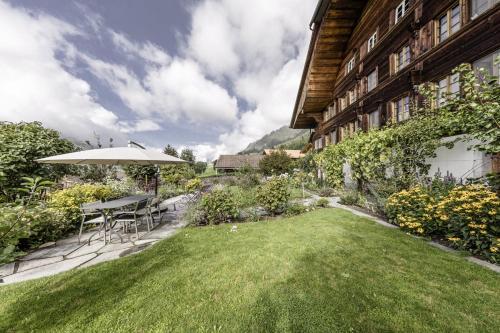 Erlenbach im SimmentalSwiss Mountain-Valley View Lodge的后院配有桌子、雨伞和草坪