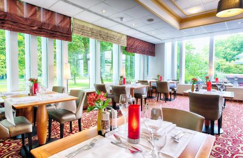 汉堡汉堡市北莱昂纳多酒店的餐厅设有桌椅和大窗户。