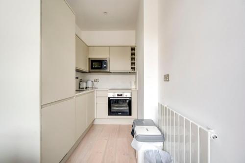 伦敦GuestReady - City Chic Living near British Museum的小厨房配有白色橱柜和卫生间。
