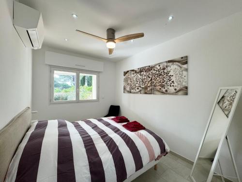滨海卡瓦莱尔Appartement 3ch avec terrasse et jardin à 400m de la plage的一间卧室配有一张床和吊扇