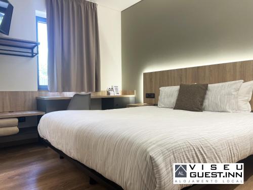 维塞乌Viseu Guest Inn的酒店客房设有一张大床和一张书桌。