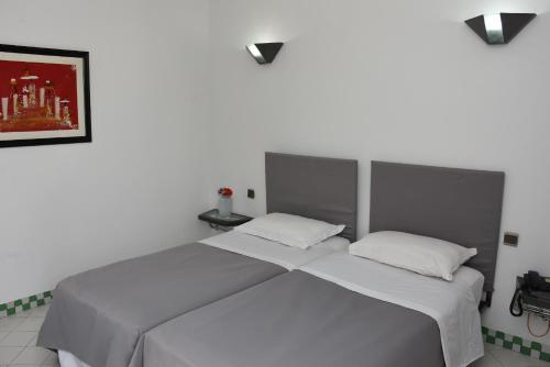 阿加迪尔塔贾德特公寓式酒店的卧室内配有两张单人床,墙上挂着一幅画