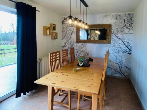 索尔布罗特Picture perfect Holiday Home in Sourbrodt with Garden BBQ的一间带木桌和镜子的用餐室