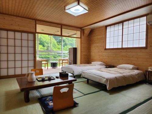 日光大和屋ホテルいろは的客房设有两张床、一张桌子和窗户。