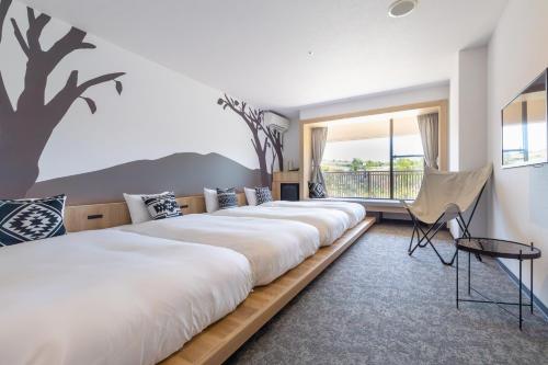 Miki神户雀巢度假酒店的有一排床,在一间有树壁画的房间