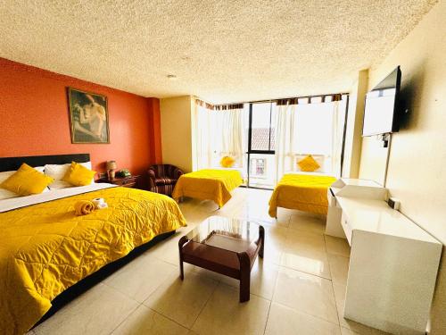 昆卡Hotel Las Americas的一间卧室拥有橙色的墙壁,床上铺有黄色的床单。