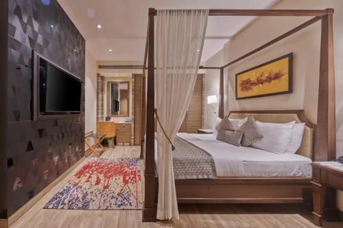 孟买福特住宅酒店的一间卧室配有一张天蓬床和一台电视机