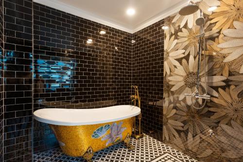 海阳BO Hotel的带浴缸的浴室和黑色瓷砖墙