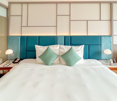 芽庄Seaesta Nha Trang Hotel的卧室配有一张带两个枕头的大白色床