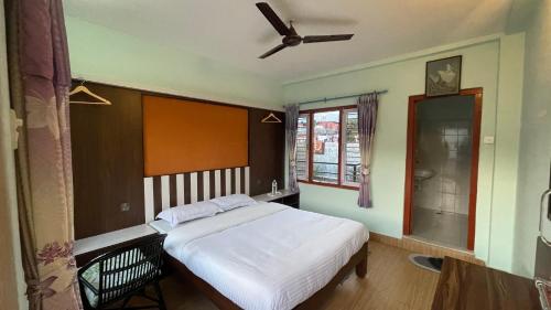博卡拉油菜花山林小屋的一间卧室配有一张床和吊扇