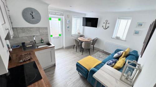 圣艾夫斯ABOVE ST IVES PORTHMINSTER BEACH - "St James Rest" is a REFURBISHED & SUPER STYLISH PRIVATE APARTMENT - King Bedroom with Ensuite, Family Bathroom, Double Bunk Cabin & Sofabed LoungeKitchenDiner - 2 mins walk Main Car Park & Station的一间带蓝色沙发的客厅和一间厨房