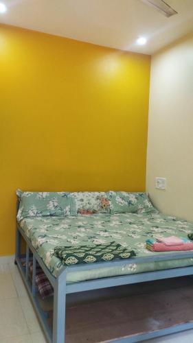 马尔万आंगण होम स्टे的黄色墙的房间里一张床位