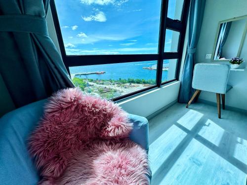 哥打京那巴鲁JQ1 SEA & POOL or CITY View WIFI I WASHING MACHINE for Seaview unit I CUCKOO WATER Jesselton Quay by R2的坐在窗前沙发上的粉红色泰迪熊