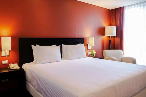 普埃布拉NH普埃布拉历史中心酒店的卧室配有一张白色大床和红色的墙壁