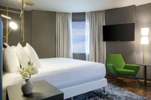 布宜诺斯艾利斯布宜诺斯艾利斯约斯顿NH系列酒店的酒店客房,配有一张床和一把绿色椅子