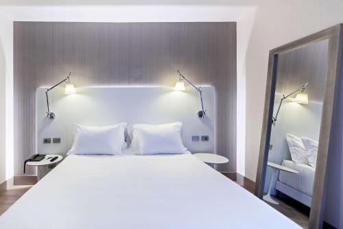 阿萨哥NH米兰会议中心酒店的一间卧室配有一张带两盏灯的大型白色床。