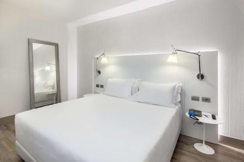 阿萨哥NH米兰会议中心酒店的白色卧室设有一张大床和镜子