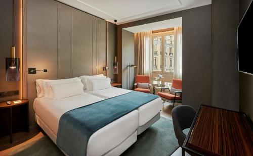 马德里马德里格兰大街乔利酒店的酒店客房设有一张大床和一张桌子。