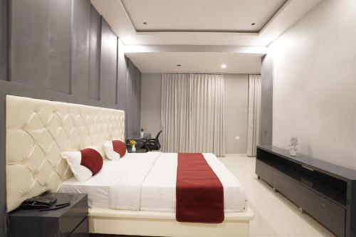 斋浦尔The Connaught House Jaipur的卧室配有带红色枕头的大型白色床
