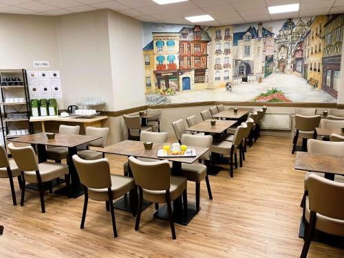 阿朗松宜必思阿朗松酒店的一间带桌椅和壁画的餐厅