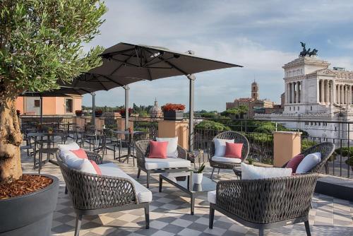 罗马NH Collection Roma Fori Imperiali的屋顶上带椅子和遮阳伞的天井