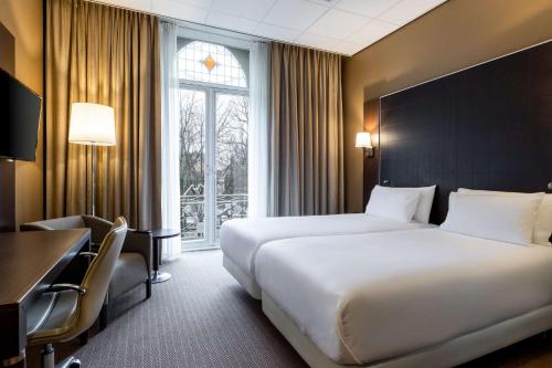 乌得勒支乌得勒支中心NH酒店的酒店客房设有两张床、一张书桌和一个窗户。