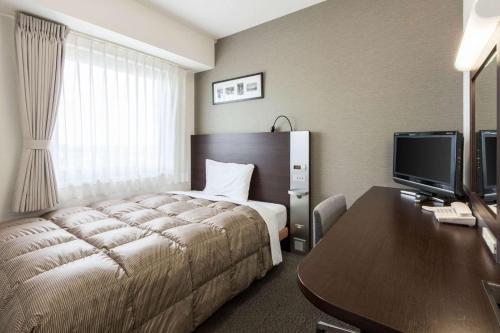 八户市八户康福特茵酒店的酒店客房配有一张床和一张带电脑的书桌