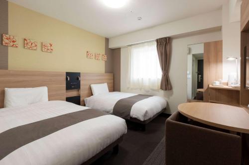 和歌山和歌山康福特茵酒店的酒店客房设有两张床和一张桌子。