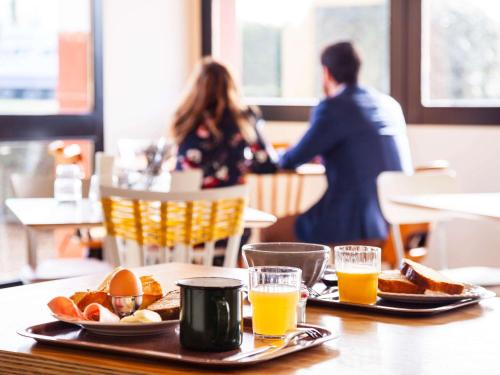 博讷greet Hotel Beaune的一张桌子,上面放着两盘食物和两杯橙汁