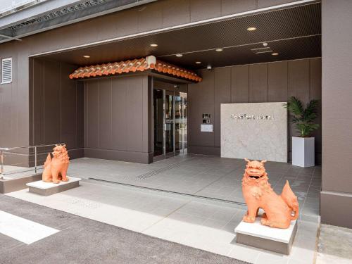 石垣岛Comfort Hotel Ishigaki Island的两座猫像在一座建筑前