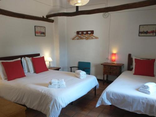 Santa Cruz de ComercioCortijo mirasol的一间卧室配有两张带红白色枕头的床