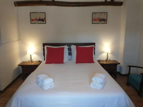 Santa Cruz de ComercioCortijo mirasol的卧室配有带红色枕头的大型白色床