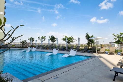 迪拜First Class 1BR Apartment in Dubai Hills - next to Dubai Hills Mall的一座配有白色椅子的酒店游泳池
